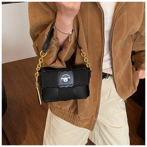 Détail d'un sac oreiller en cuir tressé noir avec chaîne dorée et écusson de chien