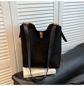 Dettaglio borsa tote in pelle scamosciata nera con chiusura girevole oro e tracolla larga