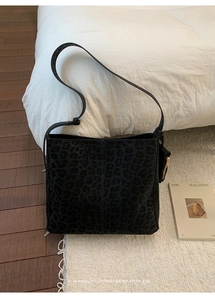 Detail of black leopard print suede tote bag with gold zipper charm in retro style