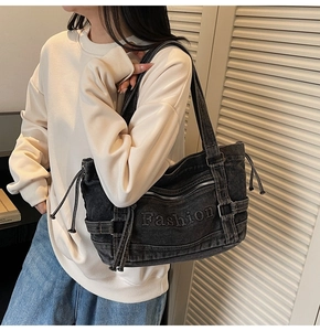 Detail of black denim tote bag with 3D Fashion lettering and side drawstring design