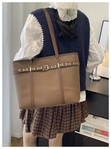 Detail of dark brown leather tote bag with gold rivets and vintage buckle decoration