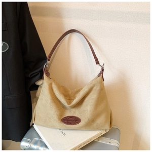 Detail of khaki suede hobo bag with leather logo patch on a metal suitcase for a travel look