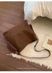Detail of dark brown leopard print tote bag with small pouch on a rustic floor
