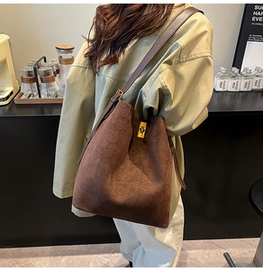 Dettaglio borsa a secchiello in camoscio marrone scuro con fibbia dorata e tracolla