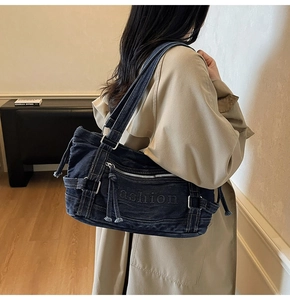 Detail of blue denim tote bag with Fashion embossing shown on model's shoulder