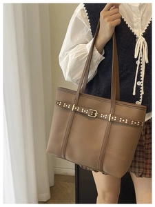 Brown litchi grain leather tote bag with gold rivets shown on a model for casual style