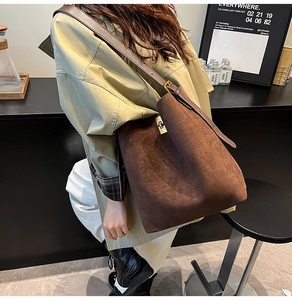 Dettaglio borsa tote in pelle scamosciata con chiusura a scatto dorata e texture