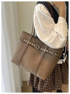 Close-up of brown litchi pattern leather tote bag with metal rivet belt buckle detail