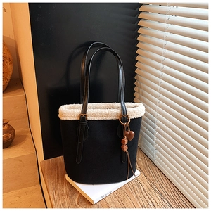 Detail of black suede tote bag featuring white faux shearling trim and heart pendant