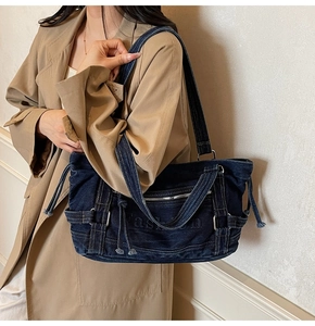 Detail of deep blue denim tote bag with drawstring and fashion embossed text on model