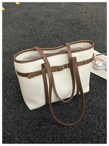 Detailed macro of beige lychee leather tote bag with brown trim and vintage metal rivets
