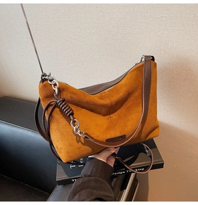 Detail of vintage brown suede tote bag featuring braided strap and silver chain accent