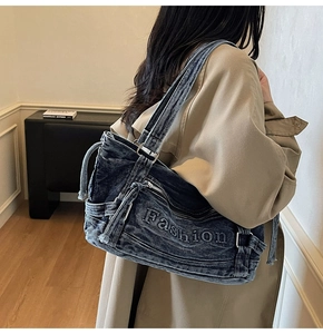 Detail of blue denim shoulder bag featuring Fashion embroidery and strap buckles