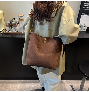Dettaglio della borsa a secchiello in camoscio marrone scuro con chiusura oro