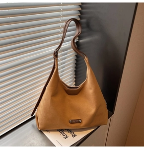 Detail of vintage brown canvas hobo bag with leather strap and metal brand tag