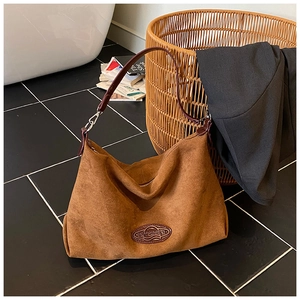 Close-up of retro brown suede hobo bag with embossed leather brand tag and zip closure