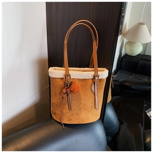 Close-up of caramel faux suede bucket bag with white fleece trim and beaded charm