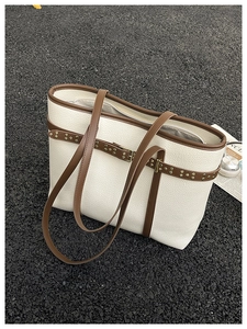 Overhead macro view of cream litchi leather tote bag with brown trim and gold studs