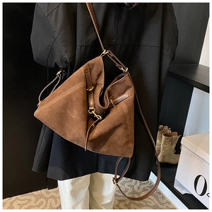 Detailed view of the brown suede tote bag with leather strap and matte gold buckle