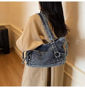 Detail shot of blue washed denim tote bag with Fashion embroidery and zipper