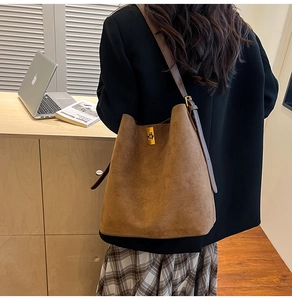 Borsa a secchiello in camoscio marrone con fibbia dorata indossata in un set elegante