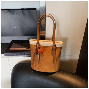 Detail of brown suede bucket bag with white faux fur trim and plush heart charm accessories