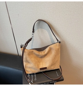 Detail of suede crossbody bag showing textured拼接 and leather woven handle on books