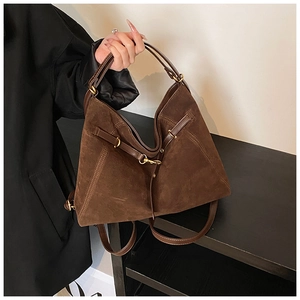 Detail of dark brown suede tote bag with leather straps and gold buckles for women