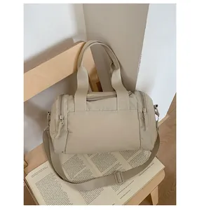 Dettaglio della borsa tote in nylon beige su sedia in legno con tracolla regolabile