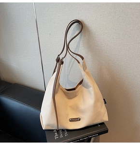 Detail view of large canvas hobo bag with leather straps and silver logo on a seat