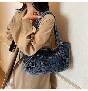 Detail of blue denim tote bag with Fashion embroidery and adjustable buckle strap