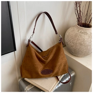Detail of brown suede tote bag with leather strap and embossed logo on vintage background