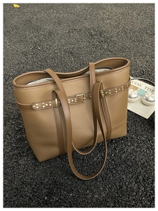 Detailed macro view of litchi texture brown leather tote bag with metallic rivet accents