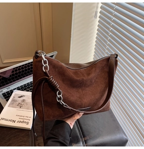 Detail of brown suede handbag with vintage leather strap and silver chain link accents