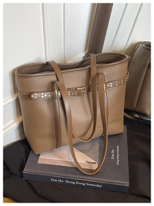 Detail of brown litchi pattern leather tote bag with gold rivets and slim shoulder straps