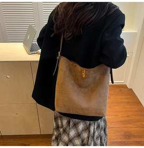 Borsa tote in camoscio marrone con chiusura dorata mostrata in un contesto d'ufficio