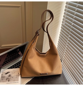 Detail of the khaki canvas hobo bag with dark brown leather strap in a warm office setting
