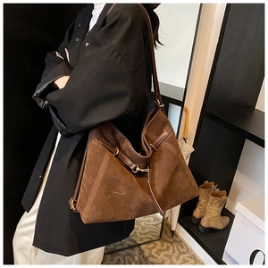 Close-up of brown suede tote bag featuring vintage gold buckles and side tie details