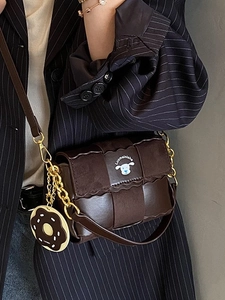 Sac oreiller tissé marron foncé avec breloque donut et chaîne dorée sur blazer