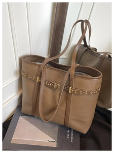 Detail of brown litchi pattern leather tote bag with gold rivet belt and zip closure