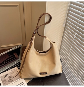 Detailed view of beige canvas tote with brown leather straps and branded logo patch