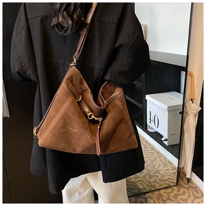 Close-up of brown suede tote bag with fine shoulder straps and metal hardware detail