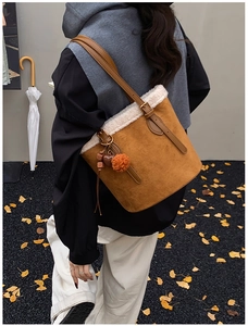 Detail of suede bucket bag with white faux fur trim and colorful heart charms