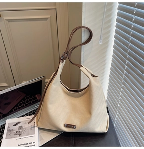Detail of minimalist cream canvas hobo bag with brown leather strap and brand logo