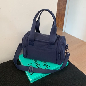 Detail view of large navy nylon travel bag with wide handles and side zipper pocket