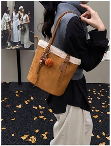 Close-up of brown suede tote bag with cream faux shearling trim and plush pompom charm