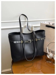Detail of black lychee grain leather tote bag with decorative rivets and gold hardware