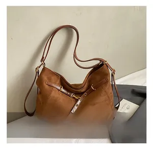 Dettaglio borsa hobo in pelle scamosciata marrone con fibbie dorate e cinturini in pelle