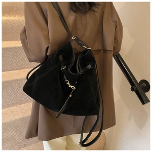 Detail of black suede tote bag with golden metal buckles and adjustable leather straps