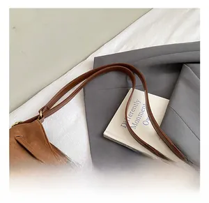 Dettaglio ravvicinato della borsa in pelle scamosciata marrone scuro con spalline in pelle